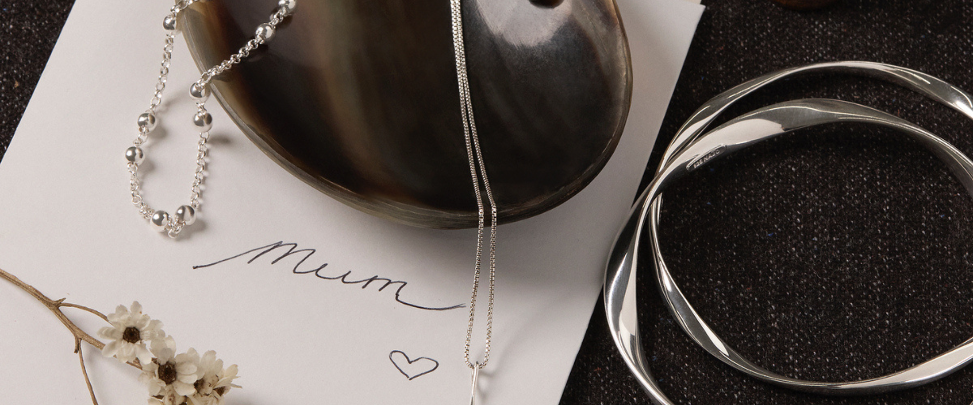 Mother holding her baby and wearing sterling silver jewellery.